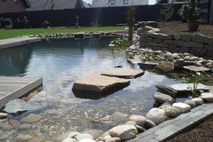 Schwimmteichanlage mit Holzterrasse und Natursteinmauer